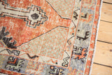 Distressed texture of a cherry red Oushak rug, showing light spandrel and primitive slate blue border.