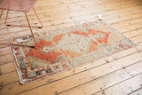 Distressed Oushak rug with abrashed cherry red field and seafoam green border of floral buds.