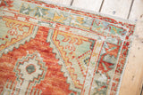 Distressed Oushak rug border showing localized etching and primitive floral buds.