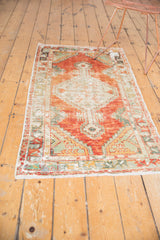 Textured corner of a vintage Oushak runner, featuring a playful red and green floral border with fringe.