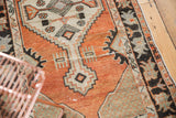 Distressed Oushak rug featuring abrashed brick red pile and ivory geometric patterns.