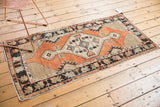 Distressed vintage Oushak runner with faded brick red field and primitive patterned charcoal border.