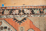 Distressed Oushak rug corner: primitive border, lattice spandrel in brick red, charcoal, sage.