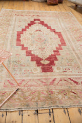 Distressed bottom border and secured fringe of a vintage Oushak rug, featuring cherry red and ivory.