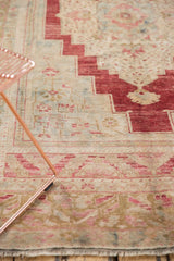 Distressed vintage Oushak rug pile, featuring blush, beige, blue patterns and fringe.