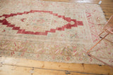 Distressed vintage Oushak rug corner, showing blush, ivory, and bronze border motifs.