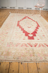 Distressed blush cherry red patterns and soft fringe on a vintage Oushak carpet.
