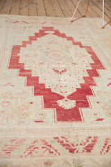 Distressed cherry red stepped medallion and ivory field on a vintage Oushak carpet.