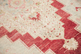 Stepped cherry red serrated border with distressed ivory field of an Oushak rug.