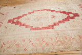 Lower corner detail of the distressed vintage Oushak rug with blush and beige motifs.