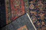 Folded Bibikabad rug reveals indigo herati pattern and tightly woven reverse with white knots.