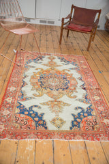 Ornate blue and orange motifs on ivory ground with a tattered red border.