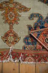 Antique Malayer rug's tattered ends, displaying the intricate red and blue floral border.