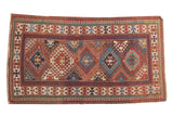 Antique Caucasian Kazak rug with central geometric medallions in madder red and blue tones.