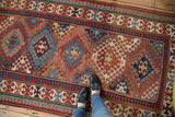 Antique Caucasian Kazak rug's madder red, blue, and saffron geometric patterns, showing time-softened pile.