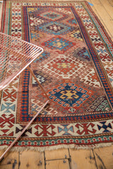 Antique Kazak rug's geometric field, with time-softened red and blue hues showcasing diminutive motifs.