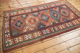 Geometric borders and field patterns on antique Kazak rug in madder red and blues.