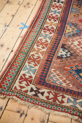 Antique Caucasian Kazak rug corner detail, vibrant geometric borders, rich reds, blues, and celadon.