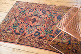 Angled view of the vintage Malayer rug's dusty blush, navy, and oxidized green half-mapped field.
