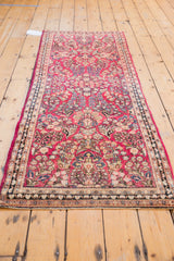 Vintage Sarouk runner's end, showing its raspberry red allover floral pattern and border.