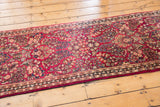 Raspberry red field and traditional border of a vintage American Sarouk runner with floral motifs.