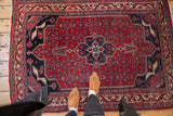 Bijar rug's cherry red herati field, dark navy trefoil medallion, and patterned ivory border.