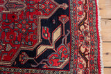 Vintage Bijar rug corner showcasing cherry red, navy, ivory geometric border, and fringe.