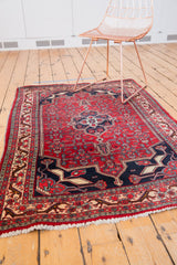 Corner of vintage Bijar rug featuring geometric herati motif, elongated rams horn design, and fringe.