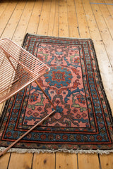 Blush Mehrivan rug corner with blue floral patterns, red accents, and visible worn fringe.