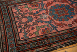 Vintage Mehrivan rug corner displaying blue floral border, blush field, and faint foundation showing.