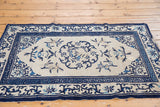 Intricate dark navy roundel and geometric cobalt borders on an ivory Peking rug, with foundation etching.