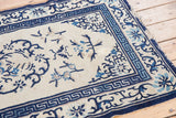 Antique Chinese Peking rug corner with ivory field and cobalt blue Running-T border.