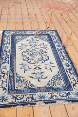 Antique Peking rug corner, ivory field, navy and powder blue running-T border with edge wear.