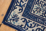 Antique Peking rug corner showing geometric Running-T border and scrolling cobalt, ivory patterns.