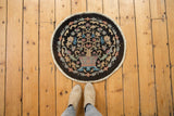 Art Deco Fette-Li style round rug with potted tree-of-life design, shown with feet for scale.