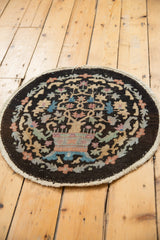 Curved edge of a vintage Chinese Art Deco round rug showing muted floral motifs and light overcasting.