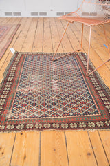 Antique Shirvan rug corner displaying red pawn borders, geometric lattice, and fringe.