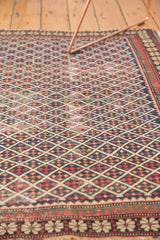 Antique Shirvan rug close-up: navy lattice field with stylized motifs and pawn design border.