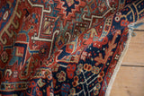 Curved vintage Karaja rug displays hand knotted geometric patterns in cherry red, navy, beige.