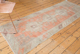 Distressed Oushak runner's geometric stepped pattern, terracotta, beige, and silver, showing worn texture.