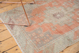 Distressed Oushak runner's geometric pattern in terracotta, beige, and aubergine with visible knot heads.