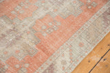Distressed terracotta Oushak runner corner with geometric beige patterns and worn pile.