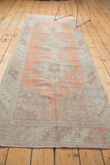 Secured end of distressed Oushak runner, terracotta and sand tones with visible foundation.