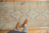 Softened peach and mint European rococo motifs on a distressed hand-knotted Oushak rug.