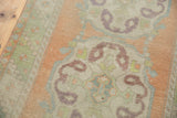 Vintage distressed Oushak runner, detail of scalloped European rococo medallion in peach and mint green.