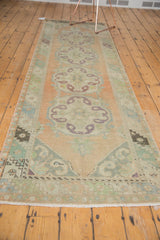 Distressed Oushak runner with even wear, featuring faded peach, mint green, and aubergine hues.