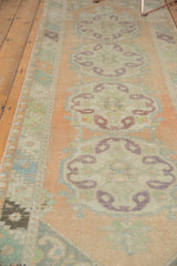 Distressed Oushak runner with softened peach, mint, and aubergine scalloped medallions.