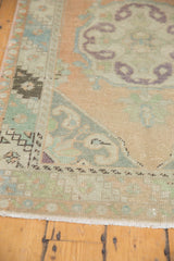 Distressed Oushak runner corner showing faded peach, mint, aubergine patterns.