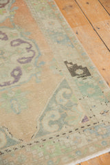 Distressed Oushak runner with scalloped mint and aubergine motifs on peach field.