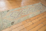 Distressed vintage Turkish Oushak runner, showing scalloped European medallion and faded peach tones.